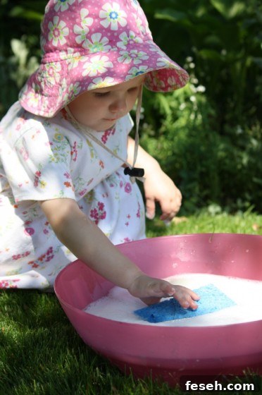 child playing with sponge in soapy water