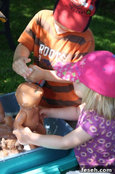 child squirting soap on doll for doll bath
