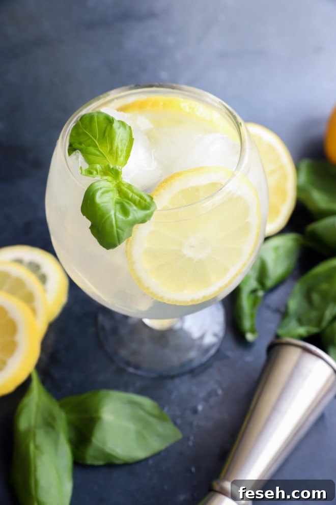 Lemon basil cocktail in a glass with basil and lemon wheel