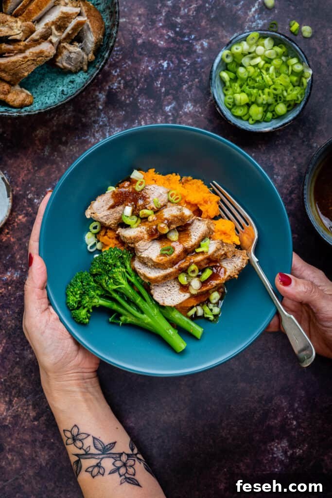Sliced pork fillet served in a bowl with sweet potato mash and steamed broccoli spears