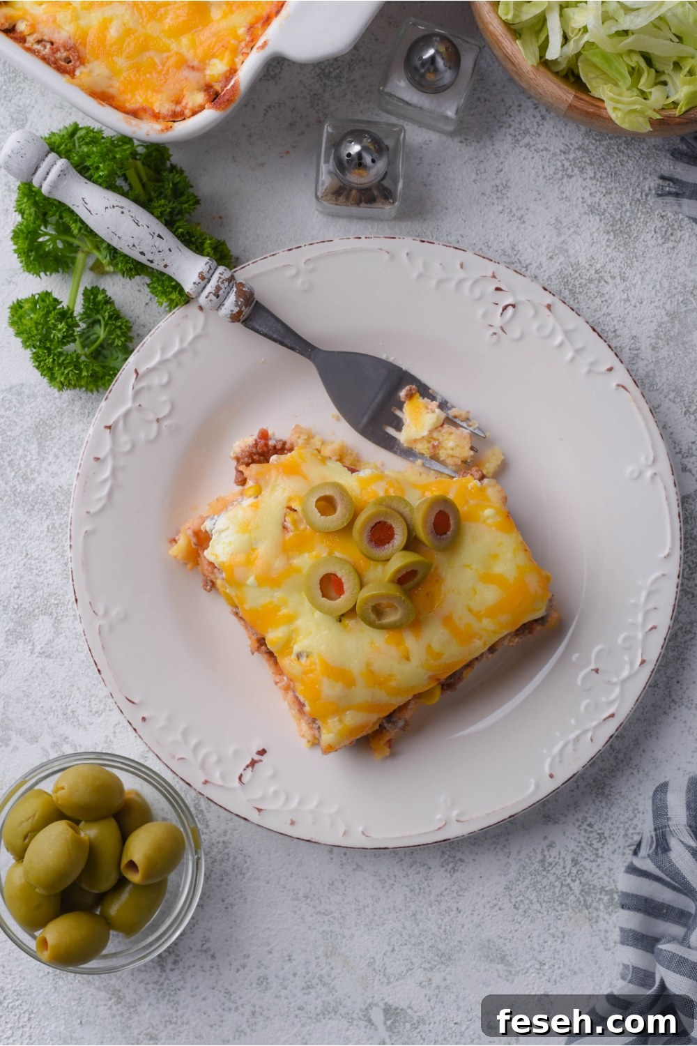 Overhead view of a serving of Mexican cornbread casserole with sliced green olives and a fork
