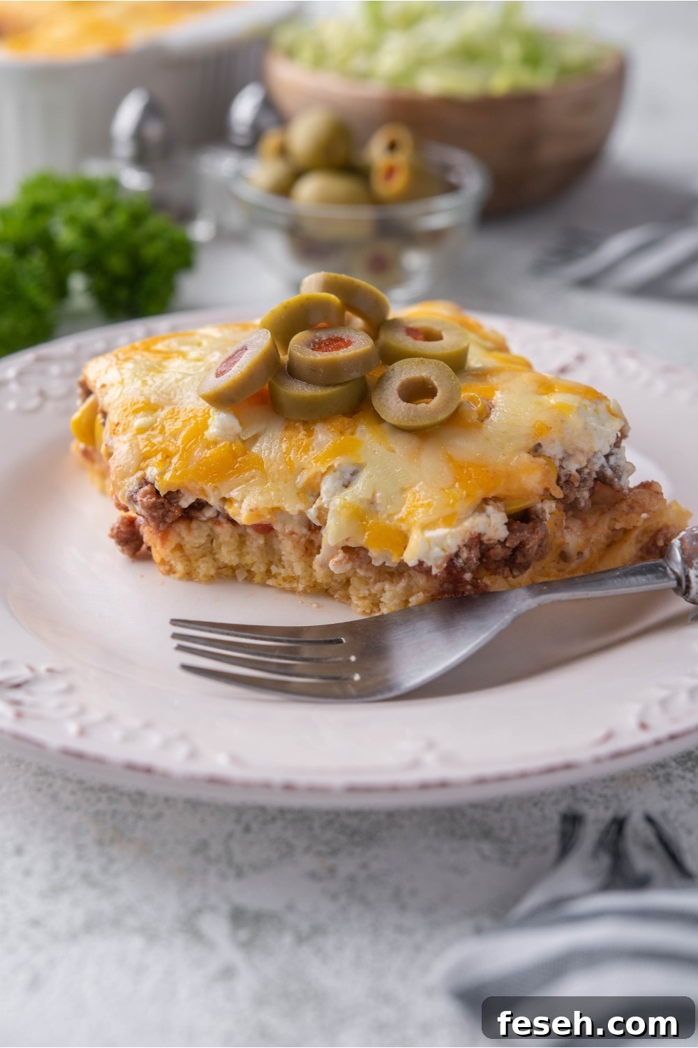 A serving of cornbread taco casserole on a white plate with garnish and fork
