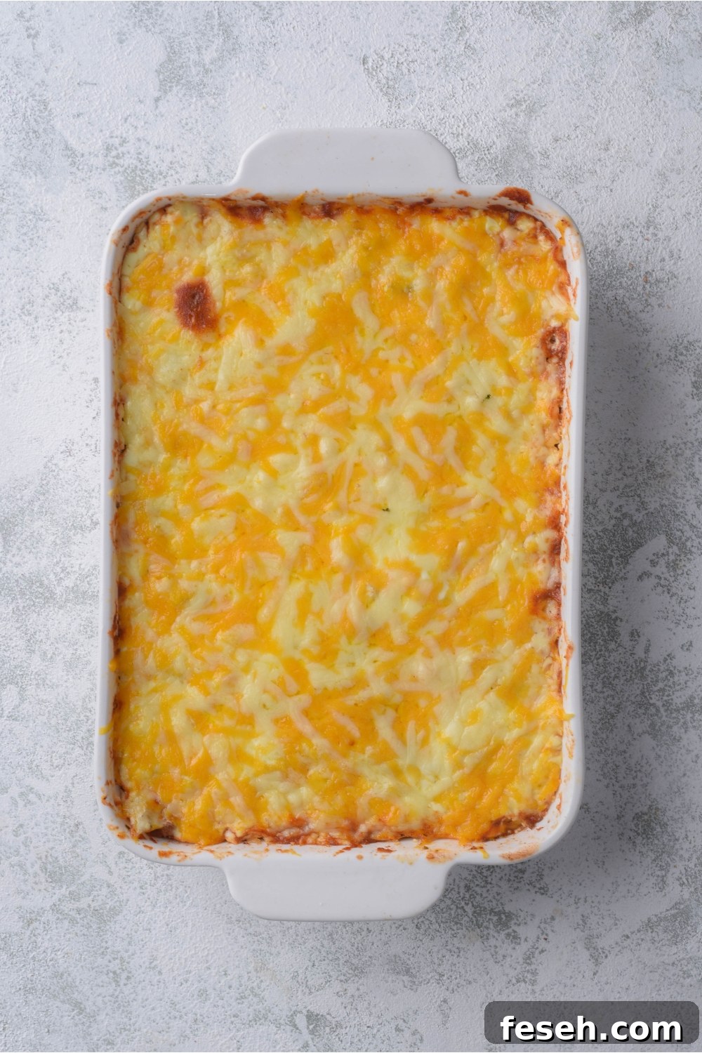 A freshly baked casserole covered in melted shredded cheese
