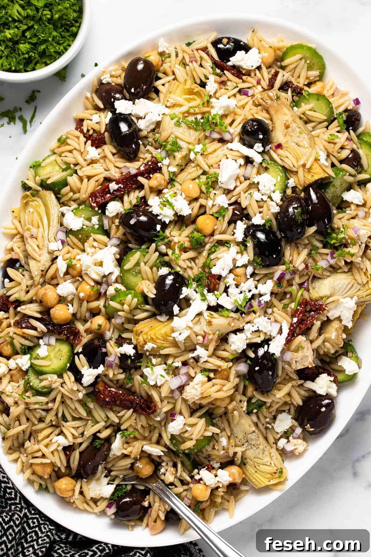Large white platter filled with Greek orzo pasta salad