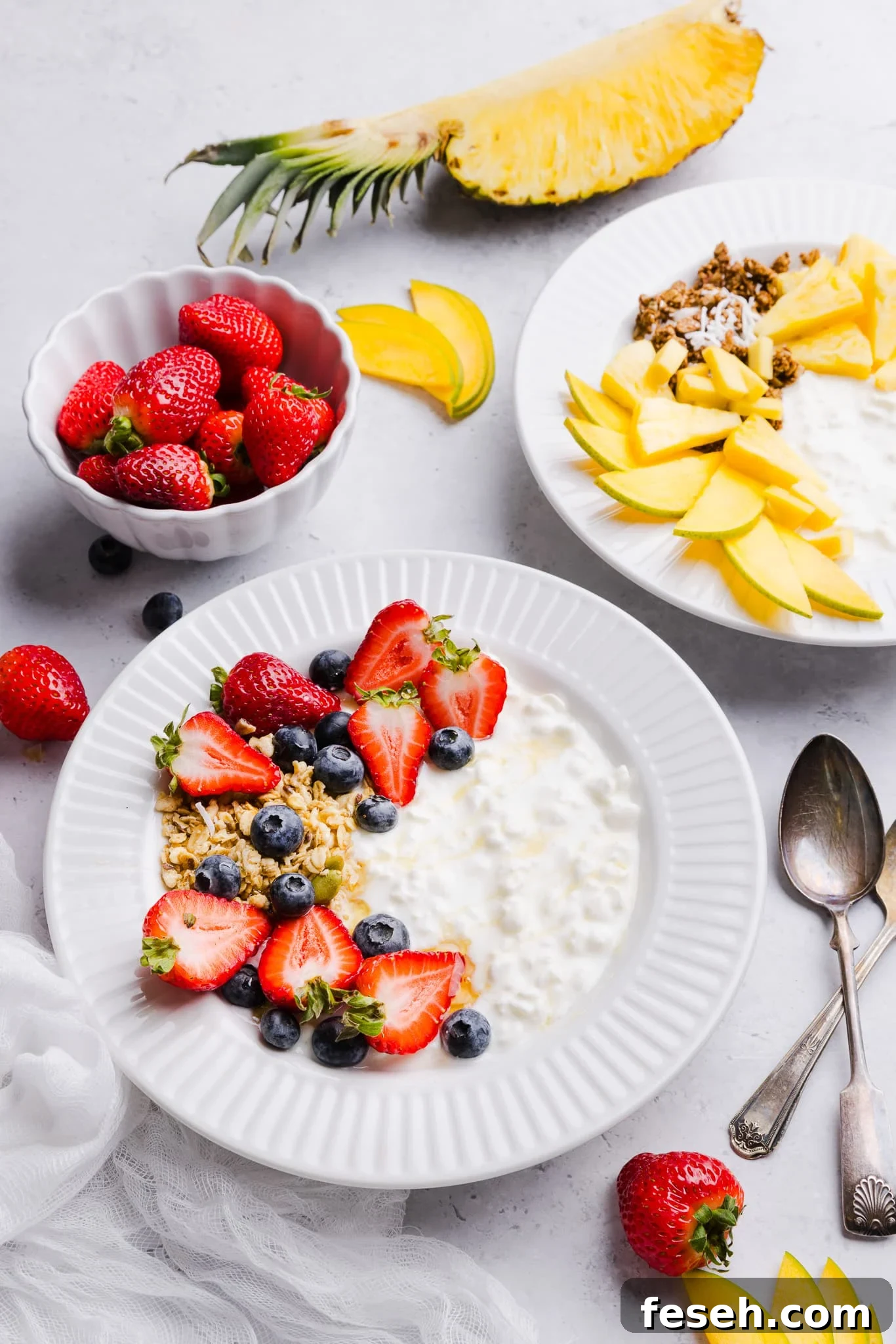 Cottage cheese and fruit bowls with various toppings like berries, granola, pineapple and mango.