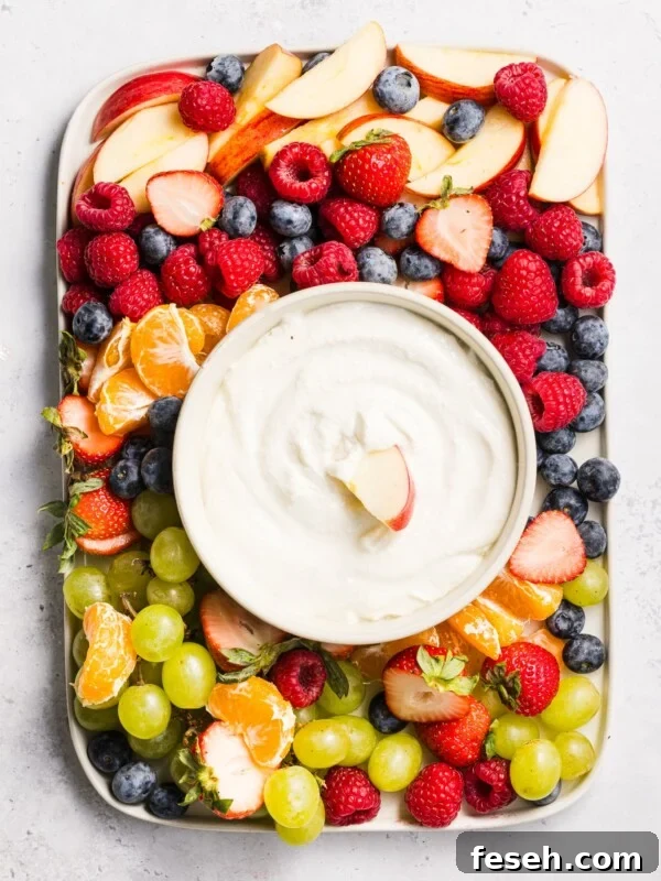 A platter of fruit with cottage cheese fruit dip in a bowl.