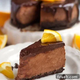 Slice of Instant Pot Chocolate Orange Cheesecake on a white plate garnished with orange slices and chocolate chips