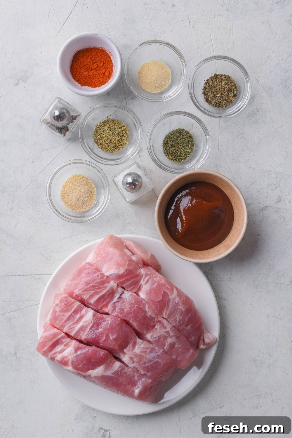 Overhead view of an assortment of ingredients including a plate of boneless pork ribs and bowls of barbecue sauce, various seasonings, and mini salt and pepper shakers.