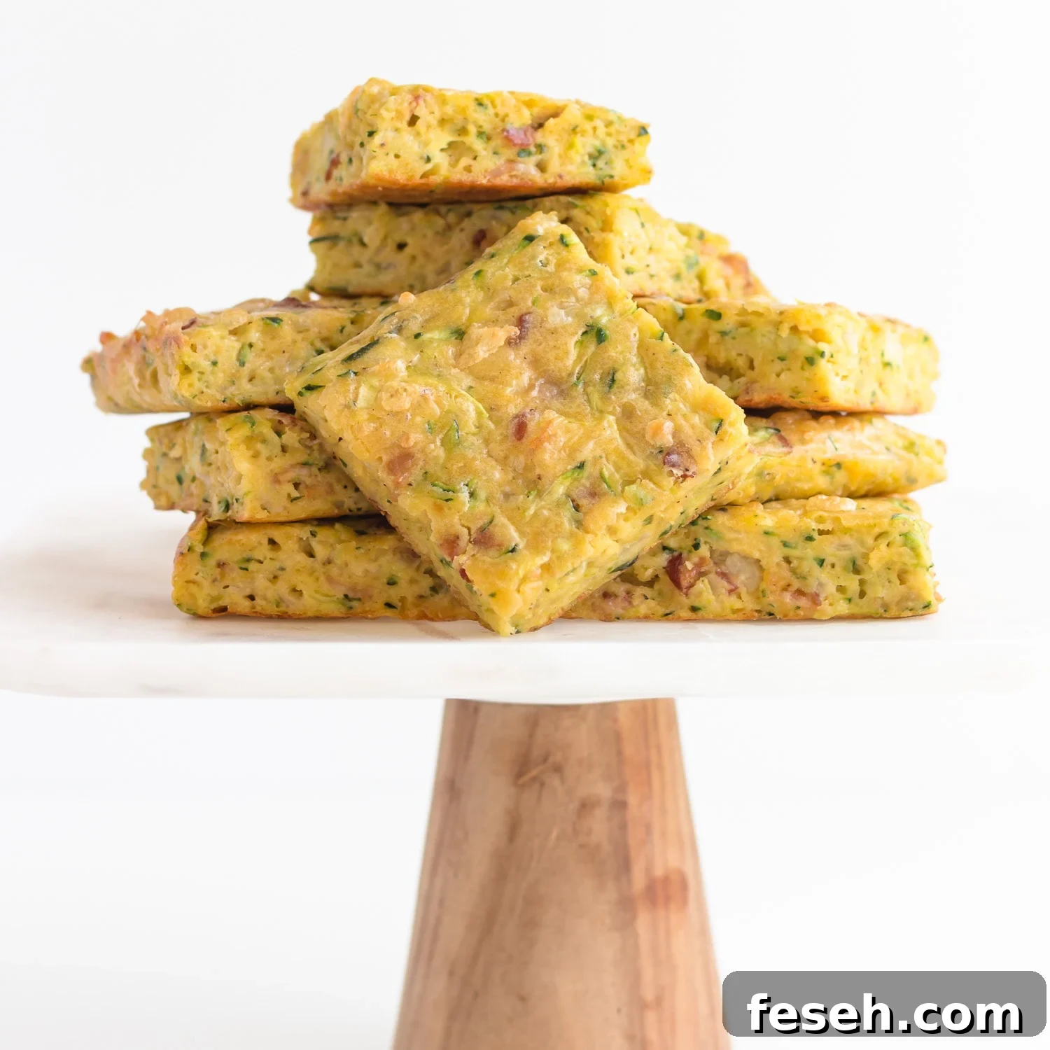 Pile of zucchini slice on a marble and wood cake stand.