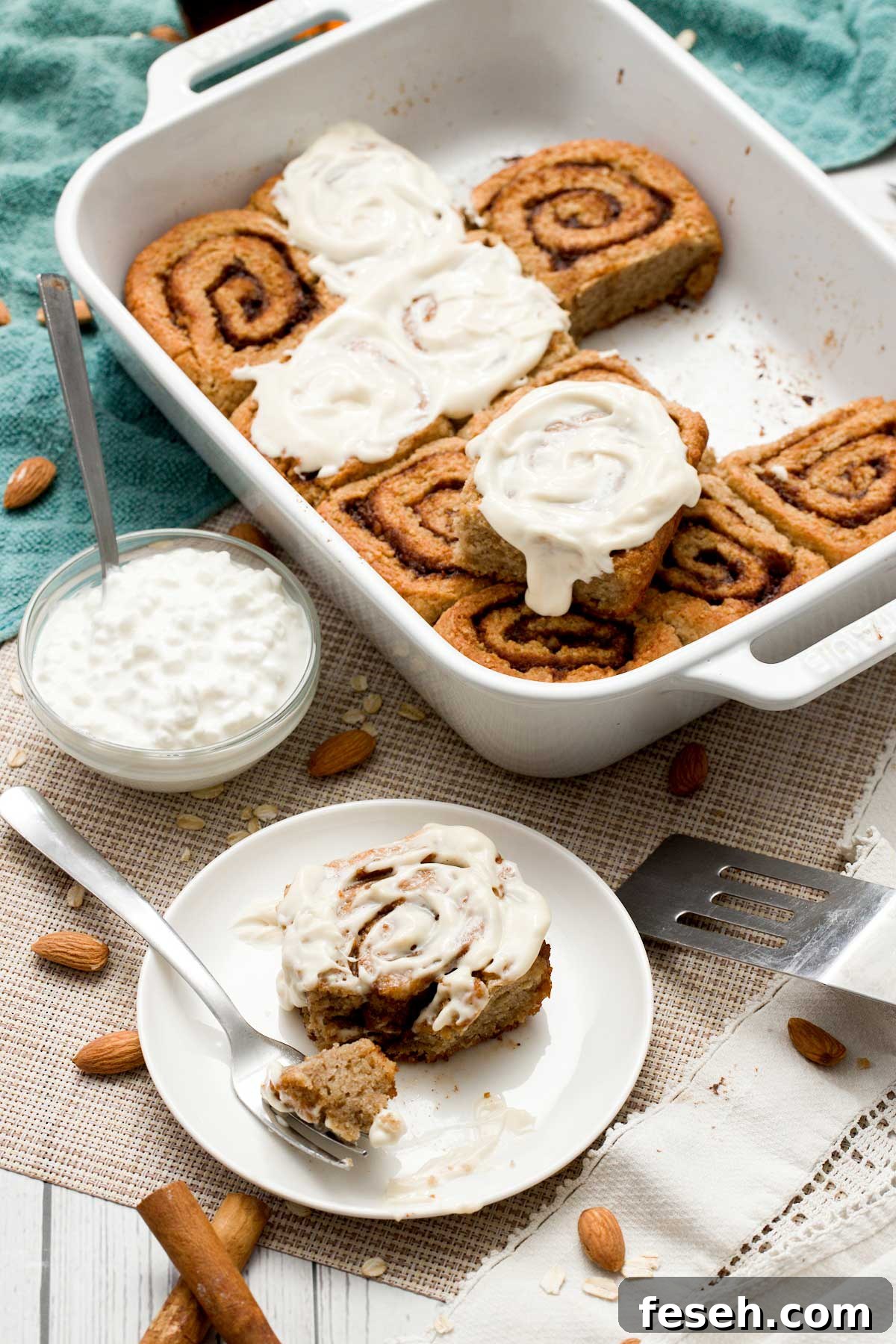 A pan and plate with gluten-free cottage cheese cinnamon rolls with a maple cream cheese spread on top.