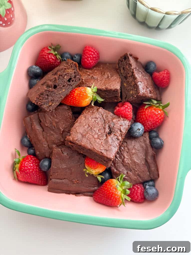 Sweet potato brownies cut into squares, served in a oven proof dish and garnished with whole strawberries and blueberries.