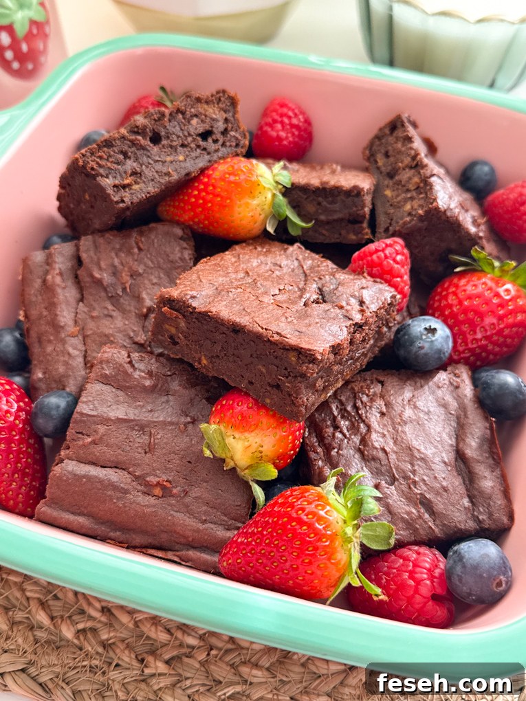 Sweet potato brownies cut into squares, served in a oven proof dish and garnished with whole strawberries and blueberries.