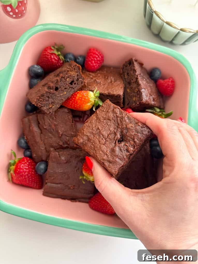 Sweet potato brownies cut into squares, served in a oven proof dish and garnished with whole strawberries and blueberries.