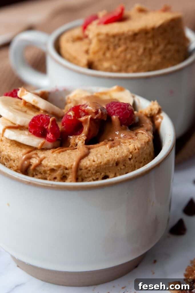 microwave baked oats in a mug with banana slices, peanut butter, and raspberries