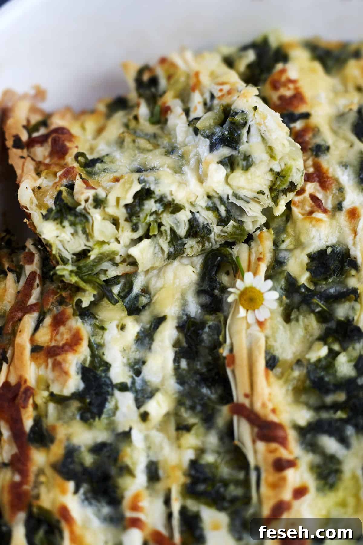 a slice of easy spanakopita recipe being lifted from a casserole dish.