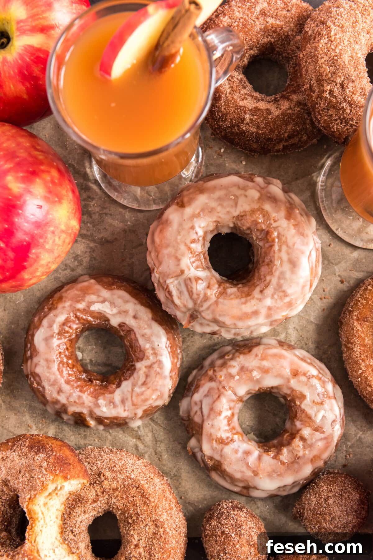 Overhead photo of Apple Cider Doughnuts with apples and apple cider in the background