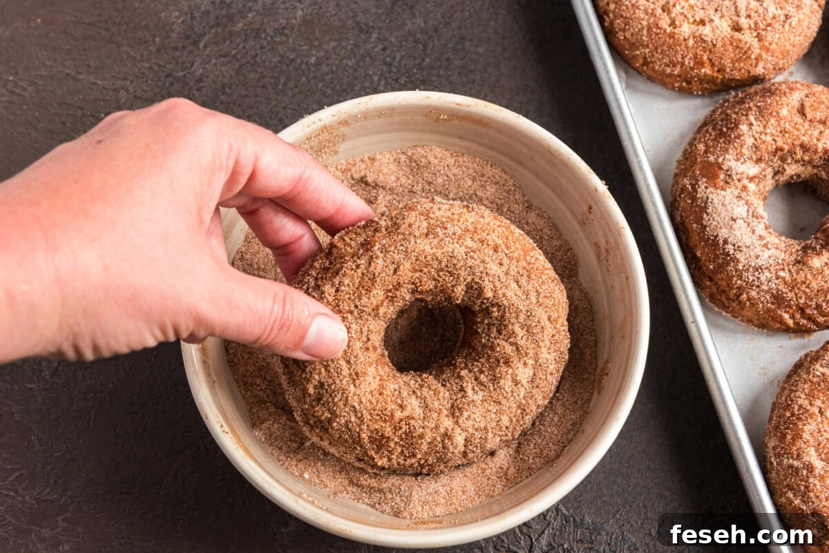 dipping fried donut in cinnamon sugar