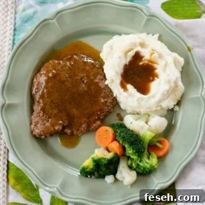 Crock Pot Cube Steak served with mashed potatoes and vegetables.