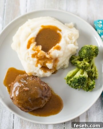 Dinner plate with a serving of Salisbury Steak, mashed potatoes, and fresh broccoli.