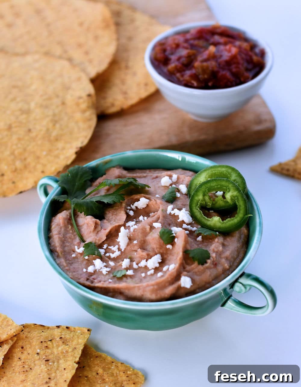24Bite: Small two-handled bowl with instant pot vegan bean dip shown with tostadas and salsa