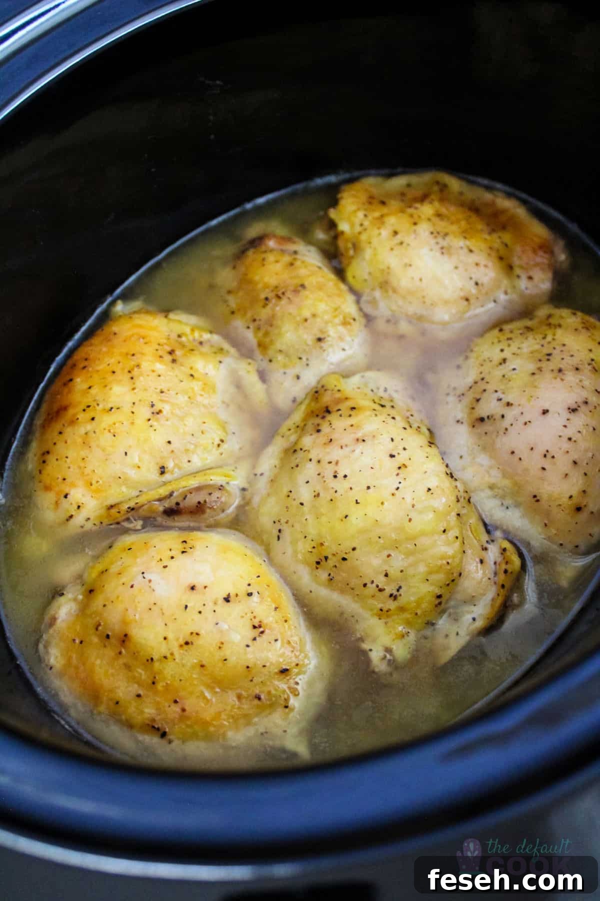 6 cooked chicken thighs in an oval slow cooker.