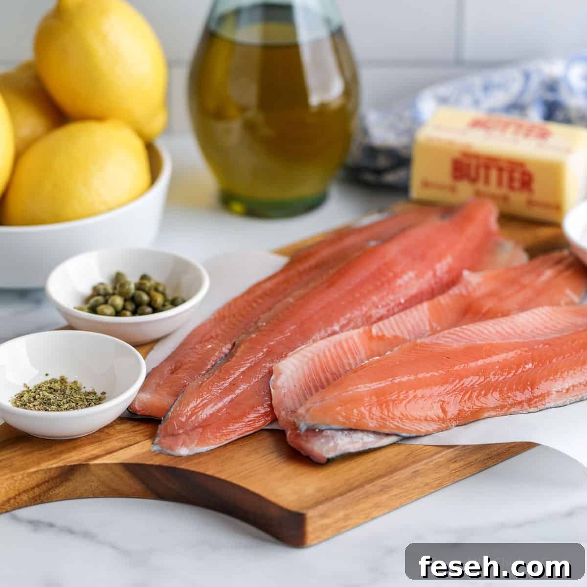 Fillets of trout next to butter, capers, lemons and seasoning.