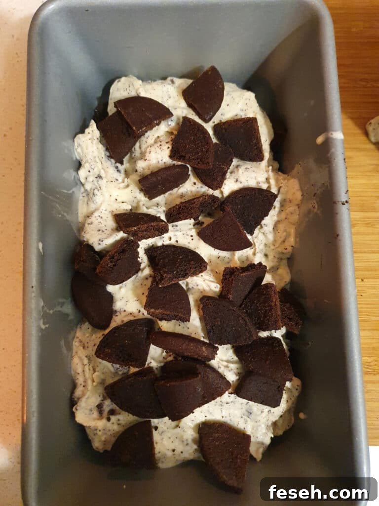 adding second layer of cookies to ice cream, about 4 to five cookies that have been cut into quarters.