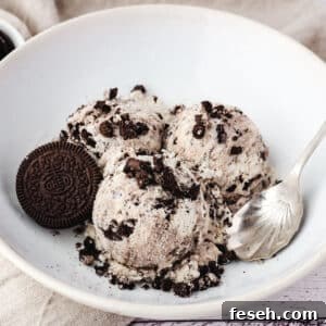 Three scoops of Oreo ice cream in a bowl with a spoon.