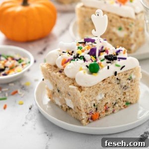 Halloween rice krispie treat, topped with seasonal sprinkles and a ghost cupcake topper, on a white plate