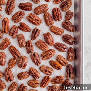 candied pecans on a piece of white parchment paper on a baking sheet