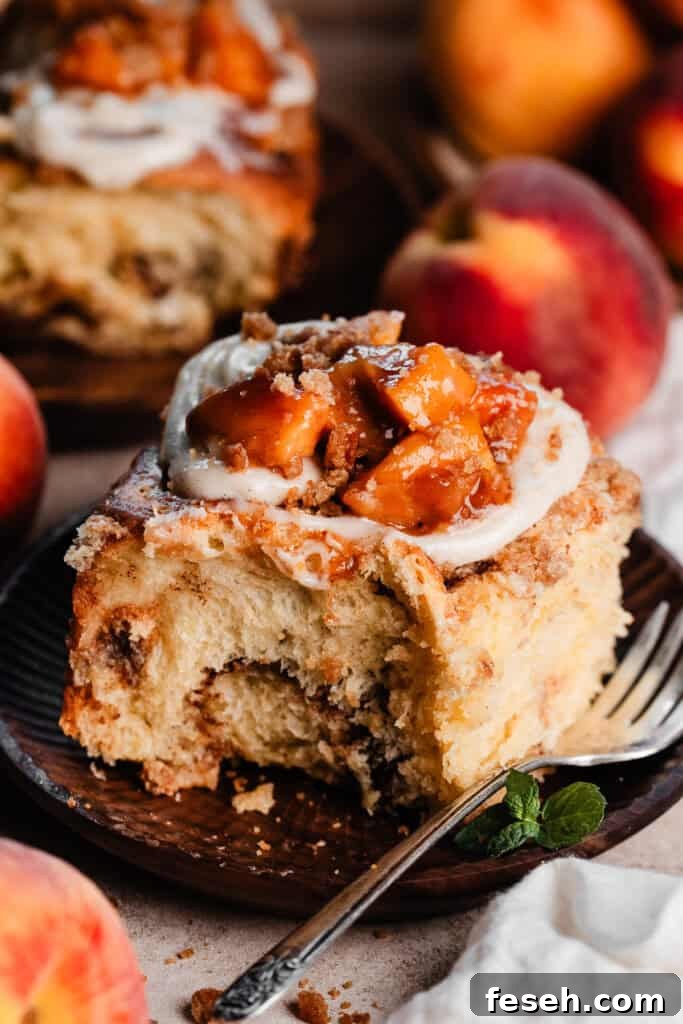 A fluffy peach cobbler cinnamon roll on a plate.