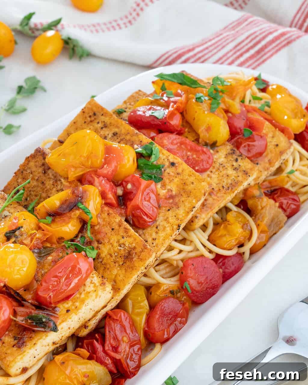 Tofu filets over a bed of tomatoes and pasta.