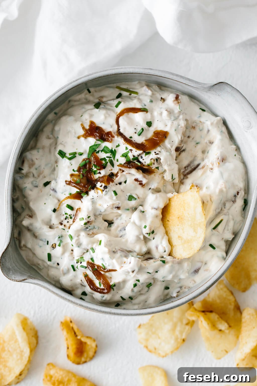 French onion dip with a potato chip scooping it up.
