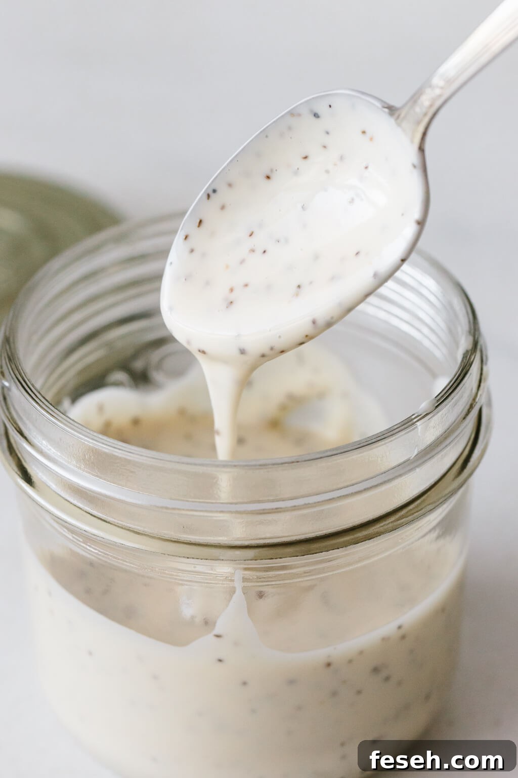 Coleslaw dressing in a glass jar with a spoon.
