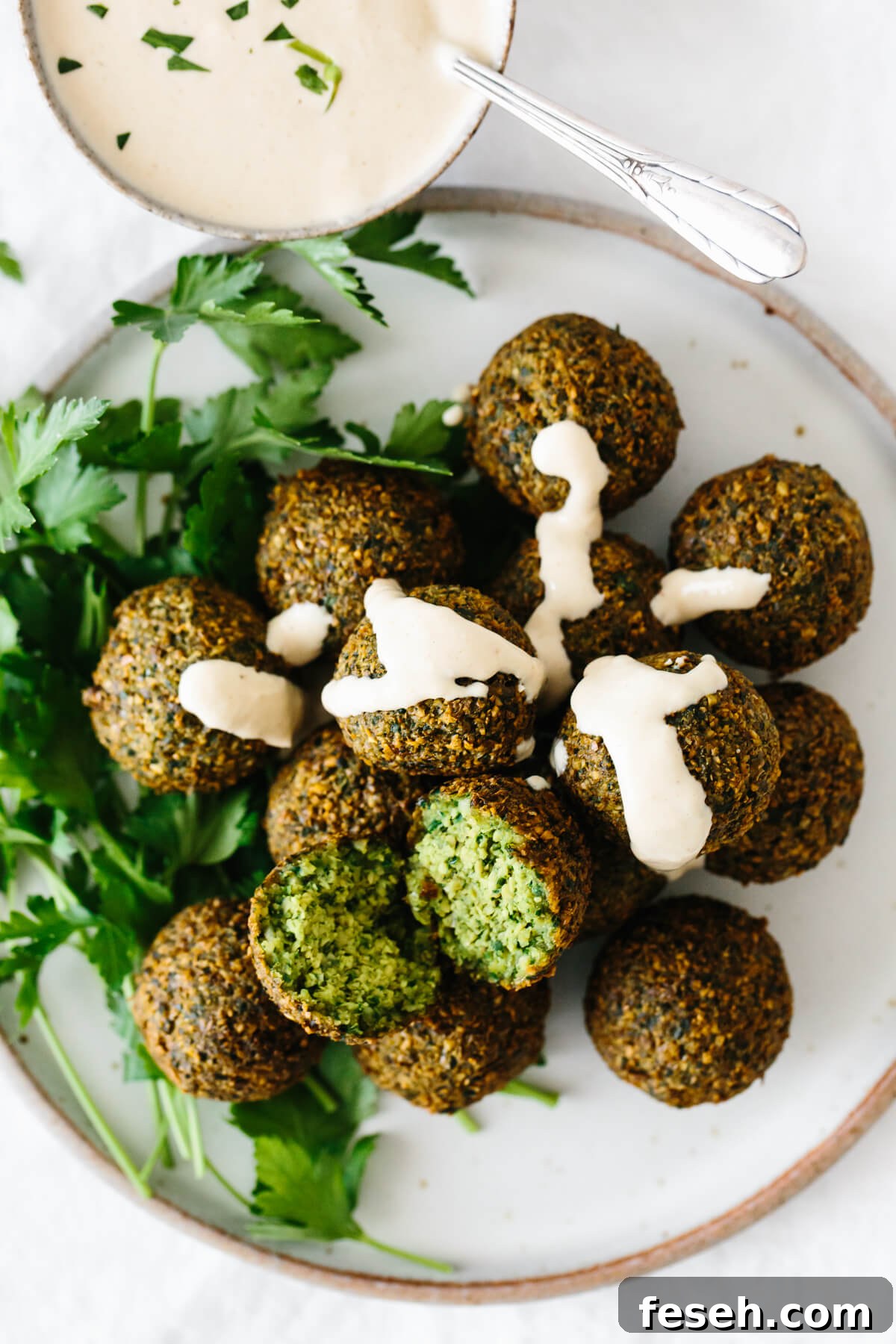 A plate of falafel drizzled with tahini sauce.