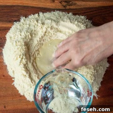 Water being added to a well of semolina flour and hand mixing.