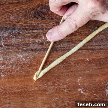 A bamboo skewer pressed into the end of a strand of dough.