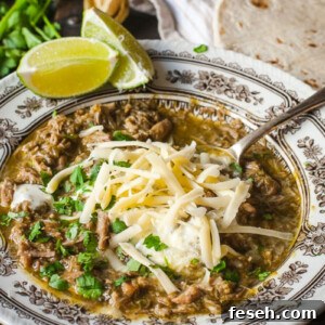 Chili Verde in a bowl topped with grated cheese and chopped cilantro