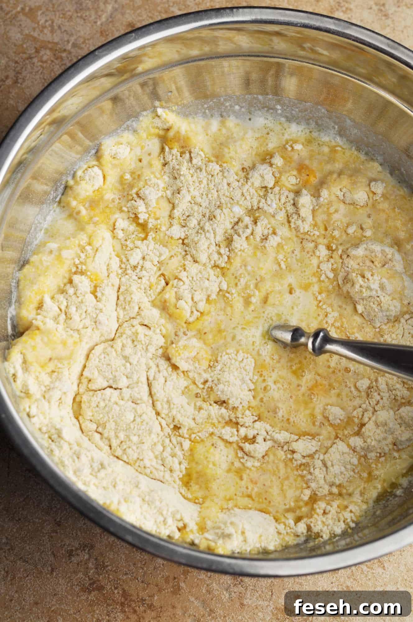 Cornmeal with eggs, milk, and melted butter mixed up in bowl.