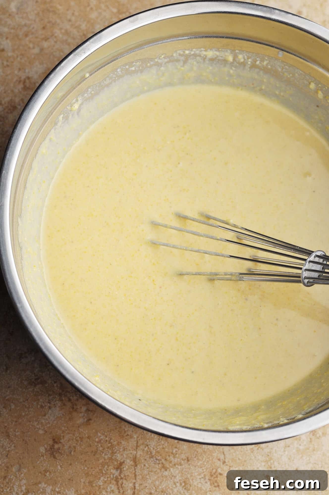 Cornbread ingredients mixed with whisk in bowl.