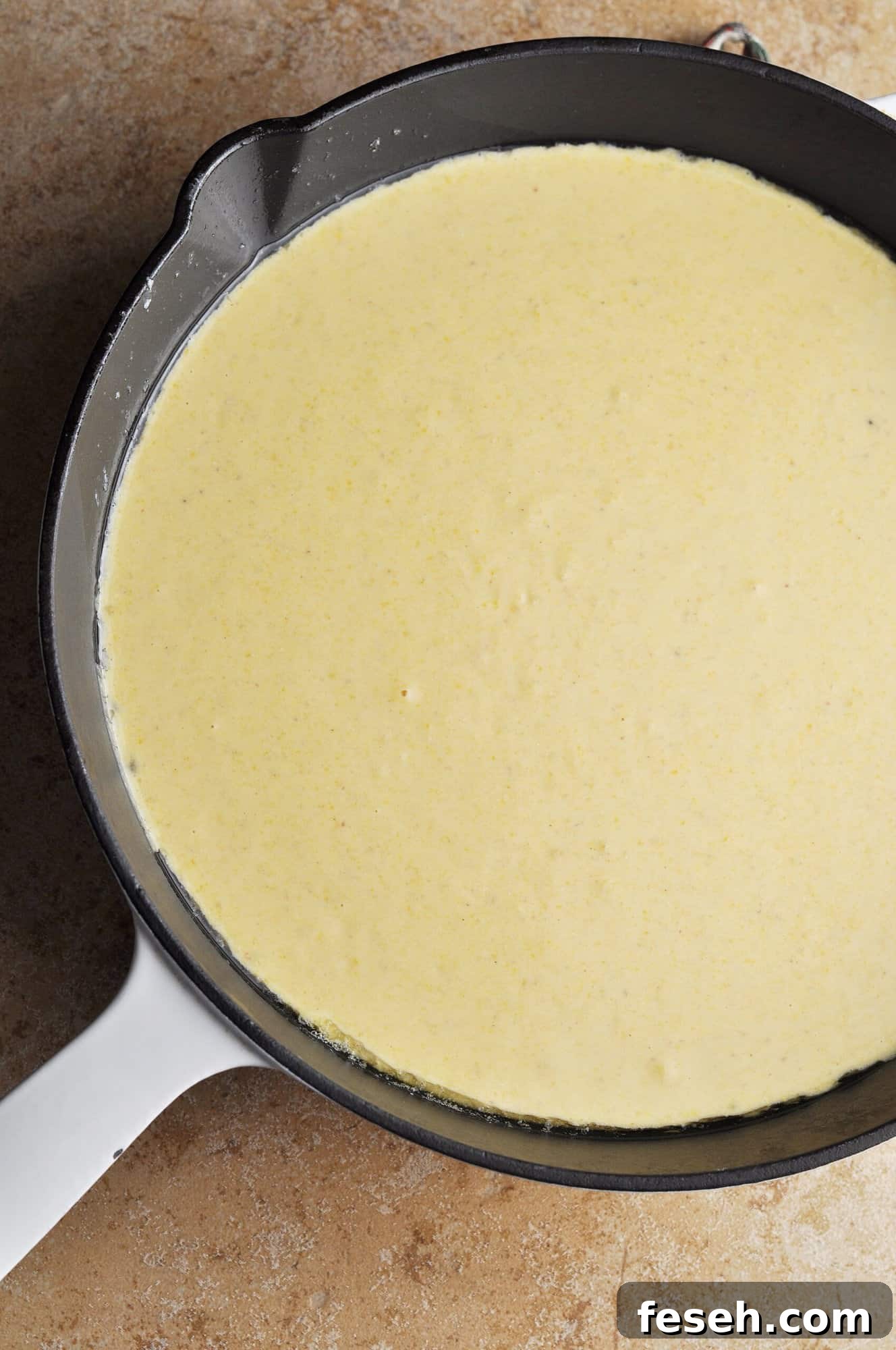 Cornbread mixture in cast iron skillet ready to bake.