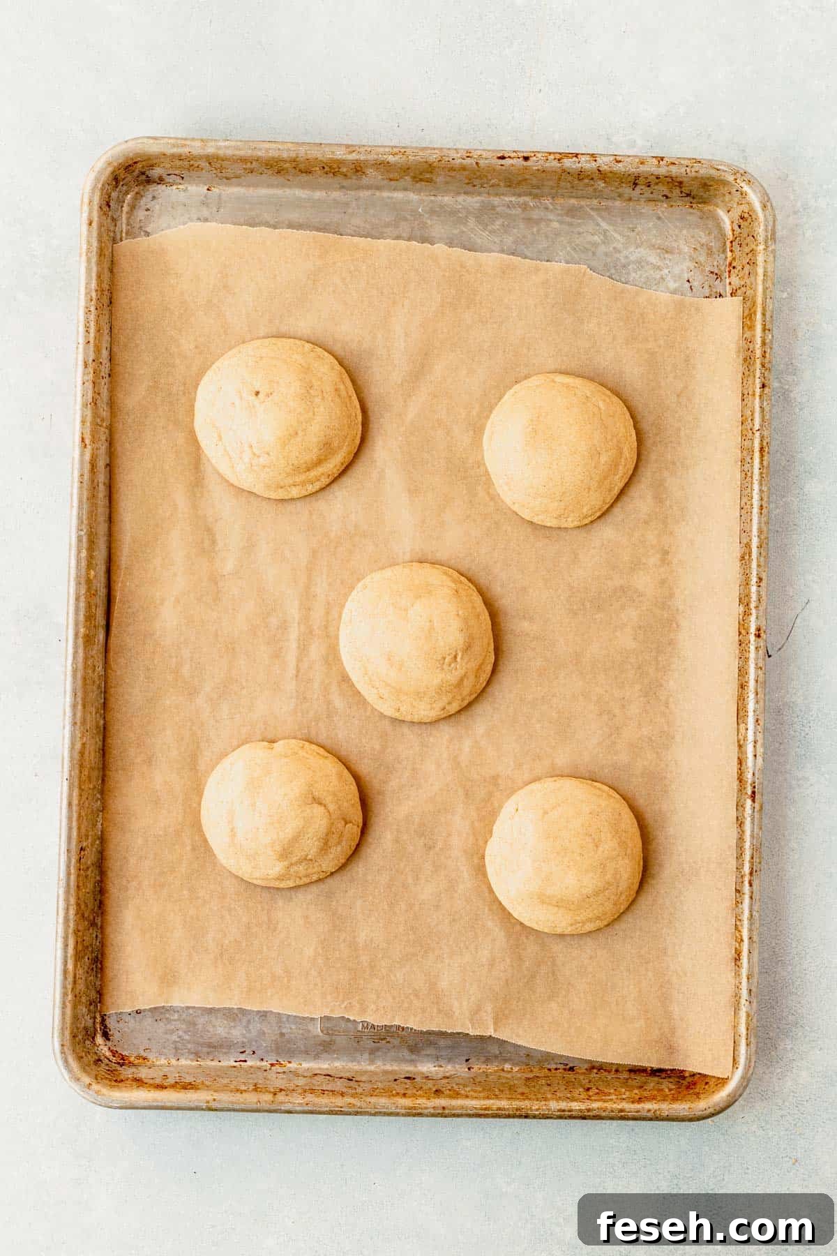 baked caramel cheesecake cookies resting on a cookie sheet.