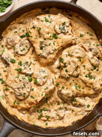 Skillet with cream of mushroom pork chops topped with chopped parsley.