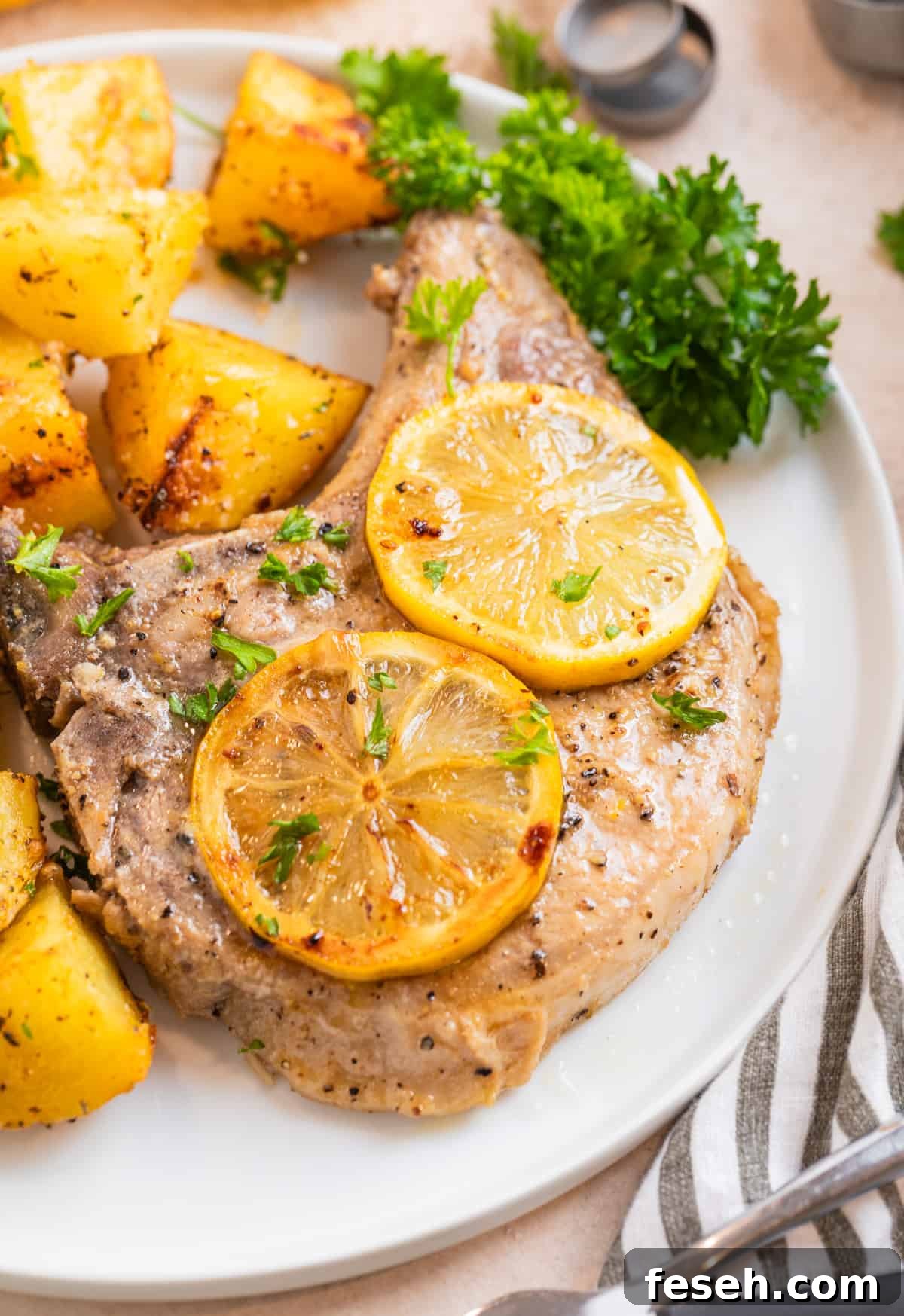 Plate with lemon pepper pork chop with lemon slices over top.