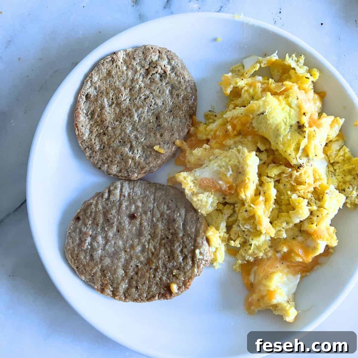 Maple chicken sausage patties next to scrambled eggs and cheese.