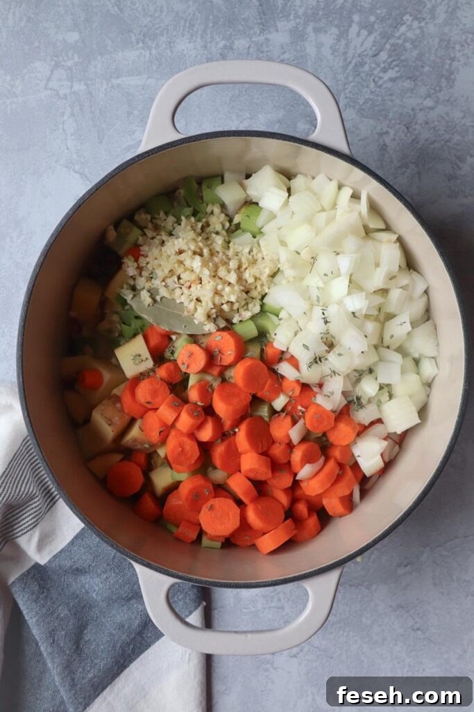 dutch oven with carrots, onion, garlic, celery, bay leaf, and potatoes