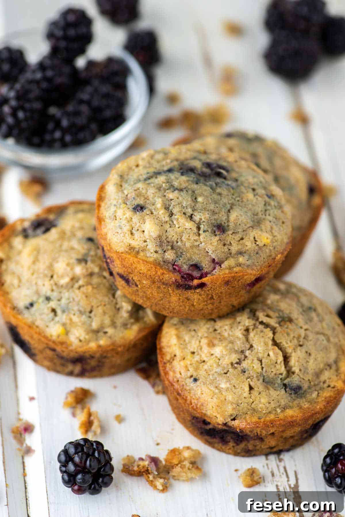 close-up of blackberry oatmeal muffin stacked on top of 3 others