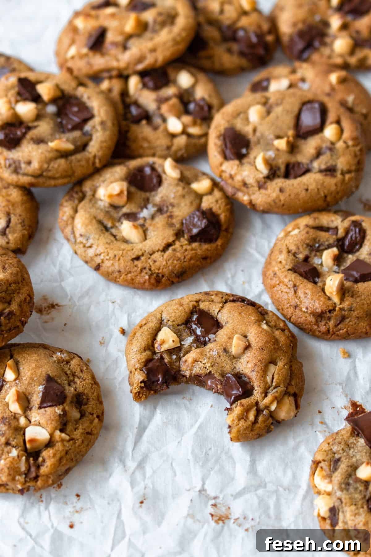 Brown butter chocolate chip cookies scattered on a white surface.