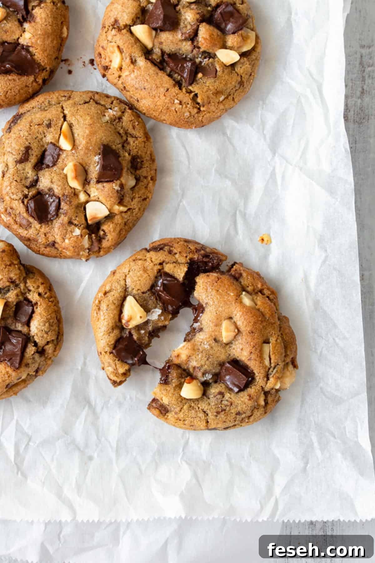 A brown butter cookie broken in half, with more cookies on the side.