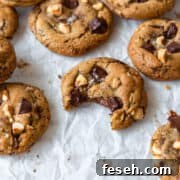 A bitten brown butter chocolate chip cookie surrounded by more cookies.